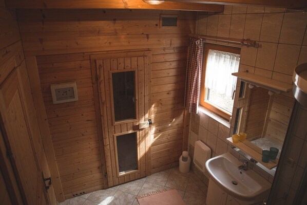 Baño de cabaña de madera con lavabo, espejo y ventana.