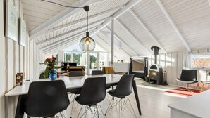 A spacious loft with a high ceiling, a dining area with modern chairs, a large window, and a wood-burning stove. - Gorgeous home in Grenaa with WiFi (Grenaa)