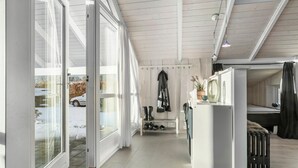 A spacious, well-lit room with large windows, a radiator, and a bench with boots and shoes. - Gorgeous home in Grenaa with WiFi (Grenaa)
