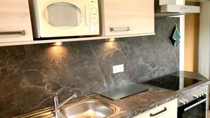 Een moderne keuken met een ingebouwde magnetron, een roestvrijstalen spoelbak en een zwarte oven.