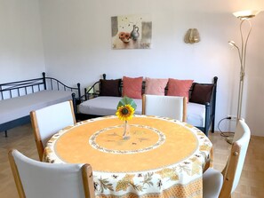 Un coin repas avec une table ronde, des chaises, un canapé et un tableau au mur.
