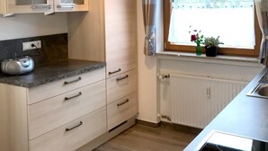 Een keuken met een raam, een radiator en een radio op het aanrecht.