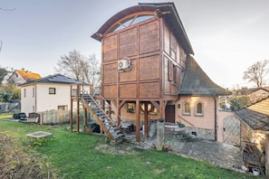 Une tour-maison en bois, dotée d’un escalier, d’un sentier en pierre et d’un petit jardin.