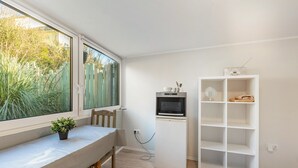 Quarto com uma mesa de jantar, um armário branco e uma janela com vista para vegetação.