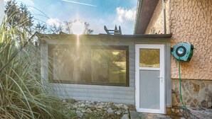 Uma casa com fachada de pedra, deck de madeira e janela com vista para um jardim.