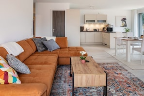Ein modernes Wohnzimmer mit einer Eckcouch, einem Couchtisch und einem gemusterten Teppich.