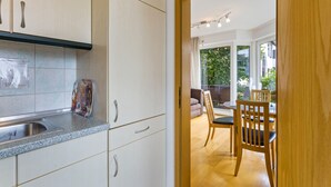 A kitchen with a sink, cabinets, and a dining area with chairs and a table.