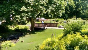 A park with a wooden bridge, a pond, and various plants.