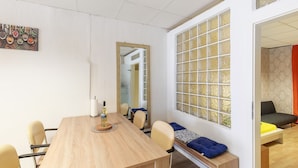 Une pièce avec une table en bois, des chaises, un miroir, une fenêtre donnant sur un beau paysage et un canapé.