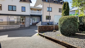 Une rue résidentielle bordée de maisons, d’une haie et d’un panneau indiquant une agence immobilière.
