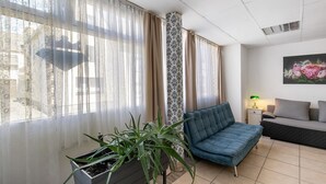 Un salon avec un canapé, une plante en pot et un tableau accroché au mur.
