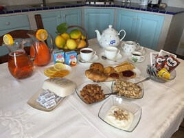 Ein Frühstückstisch mit verschiedenen Speisen und Getränken, darunter eine Karaffe Orangensaft, eine Teekanne und eine Schale Mandeln.