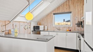 Una cocina moderna con una isla grande, un ventanal y un tragaluz.