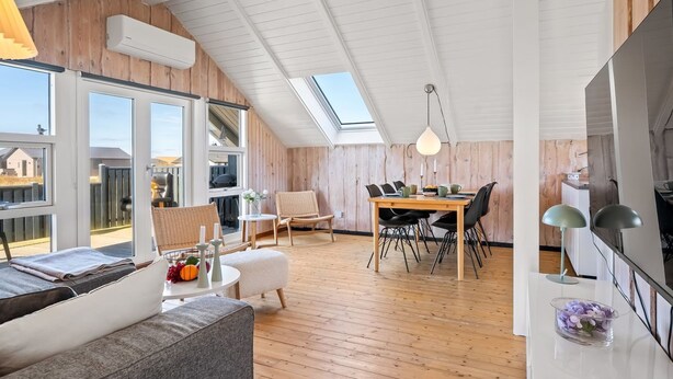Una habitación moderna estilo loft con comedor, sofá y un ventanal grande.