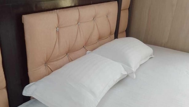 A bed with a tufted headboard and two pillows. - Banaras Home Stay By GRB (Varanasi)