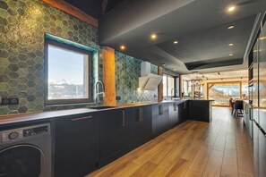 Una cocina moderna con un amplio ventanal, armarios oscuros y piso de madera.