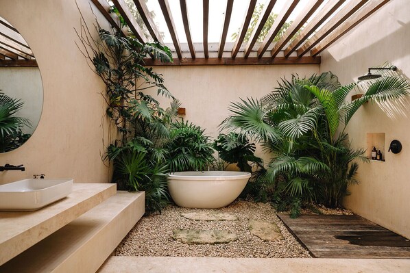 A modern bathroom with a freestanding bathtub, a sink, and a shower area, surrounded by lush tropical plants. - 4BD Tulum Jungle Home 5 Mins from Tulum Beach (Tulum)