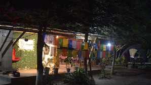 A traditional building with a covered outdoor area, potted plants, and prayer flags. - Villagelife (Mikirbheta)