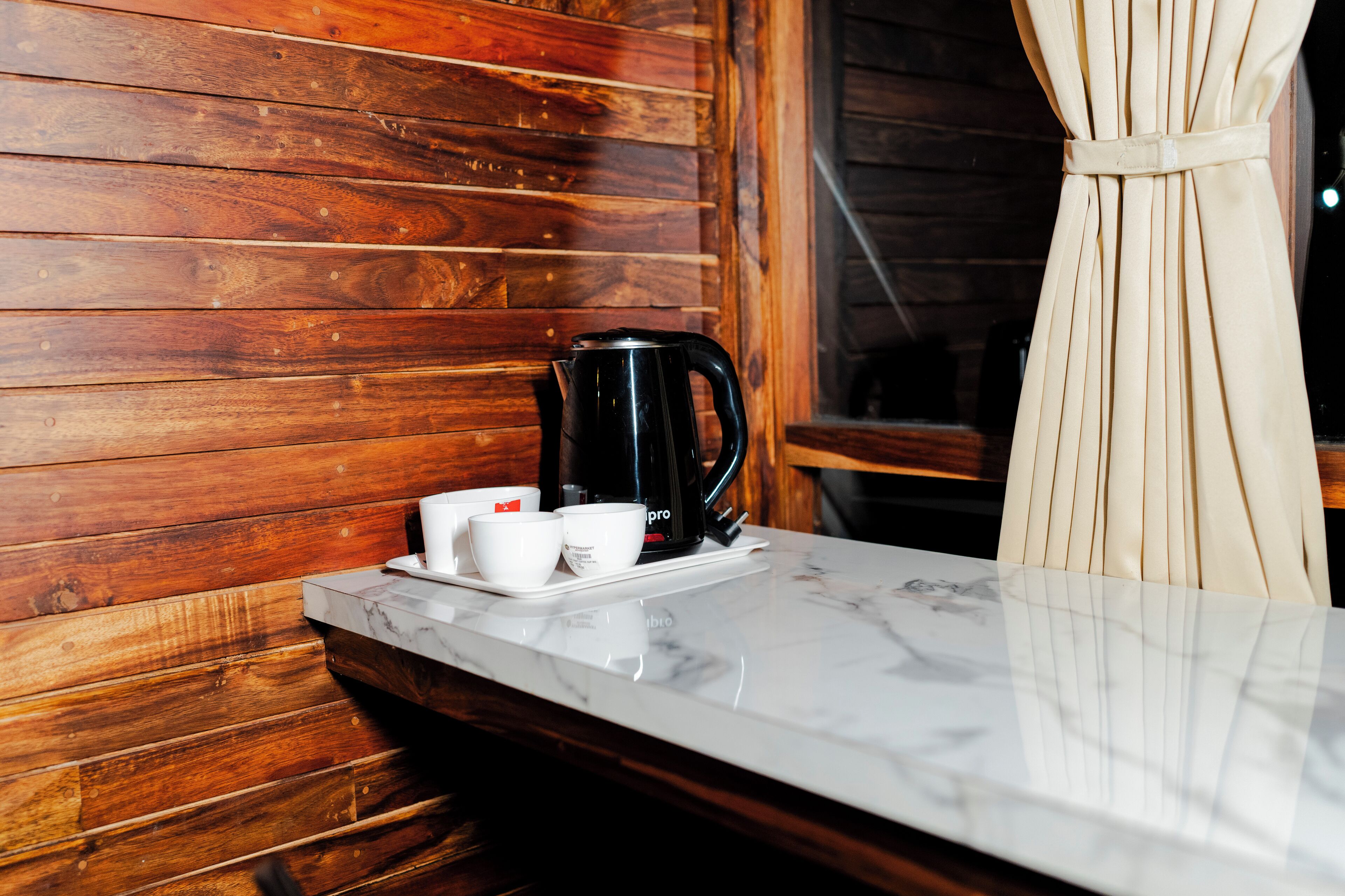 Un mur en bois, une machine à café noire et un comptoir en marbre blanc.
