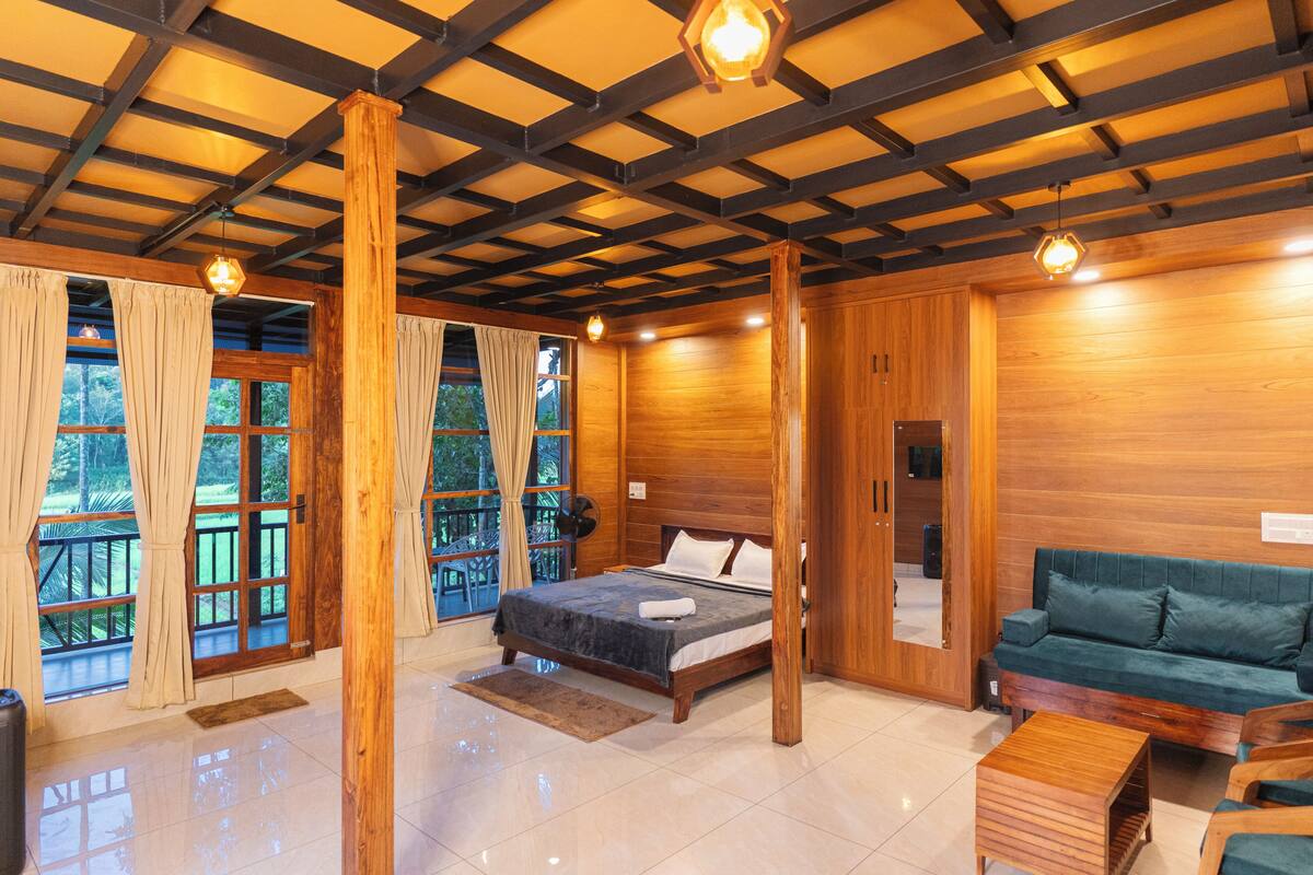 A wooden-floored bedroom with a bed, a green sofa, and a wooden coffee table.