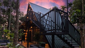 A modern building with a metal roof and wooden beams, surrounded by tropical vegetation. - Ethnic Villa Wayanad (Sulthan Bathery)