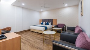 A modern hotel room with a bed, two seating areas, a desk, and a ceiling fan. - The sandalwood by Manvenco Hospitality (New Delhi)