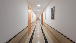 A long, well-lit hallway with doors on both sides, leading to rooms. - The sandalwood by Manvenco Hospitality (New Delhi)