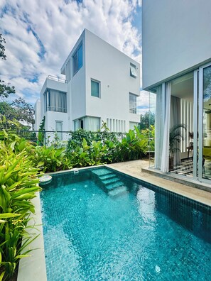 Une maison moderne dotée d’une piscine, le tout entouré d’une végétation luxuriante.
