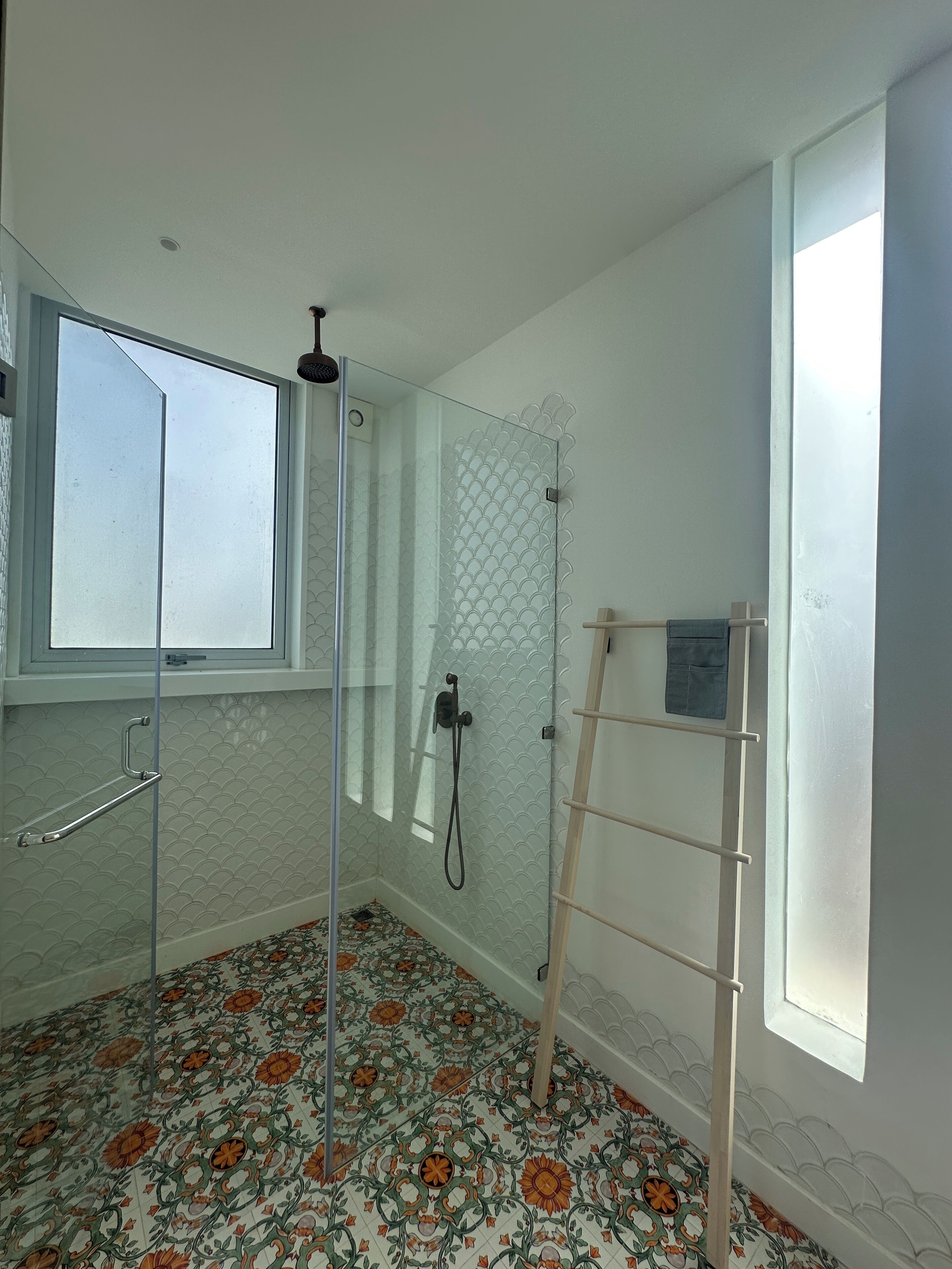 A bathroom with a shower, a window, and a tiled floor.