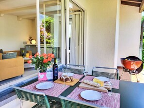 Enjoy a casual dining experience in this outdoor space with a grill, comfortable seating, and a view of lush greenery.