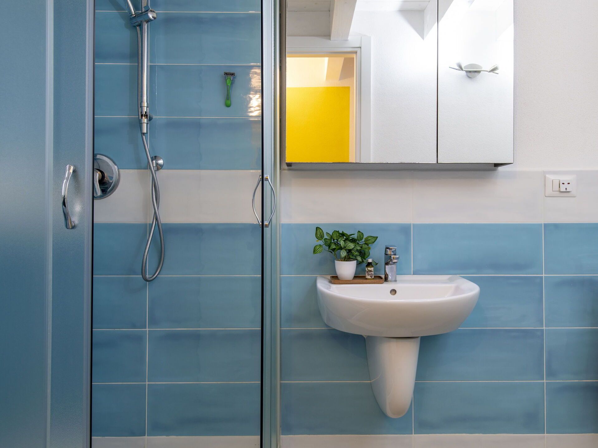 A bathroom with a shower, a sink, and a mirror.