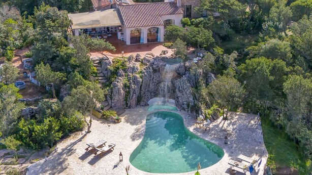 An aerial view of a resort with a pool, a waterfall, and a building with a tiled roof. - Beautiful private villa with WIFI, A/C, private pool, TV, patio, pets allowed and panoramic view (Olbia)