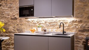 Une cuisine moderne dotée d’un four à micro-ondes encastré de la marque Bosch, d’un évier et d’un mur en pierre en arrière-plan.