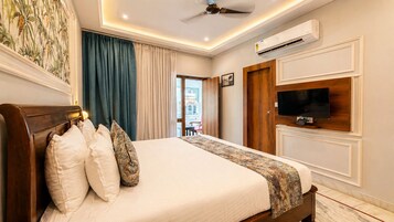 Habitación de hotel con cama, cortinas, televisor, aire acondicionado y vistas al exterior.
