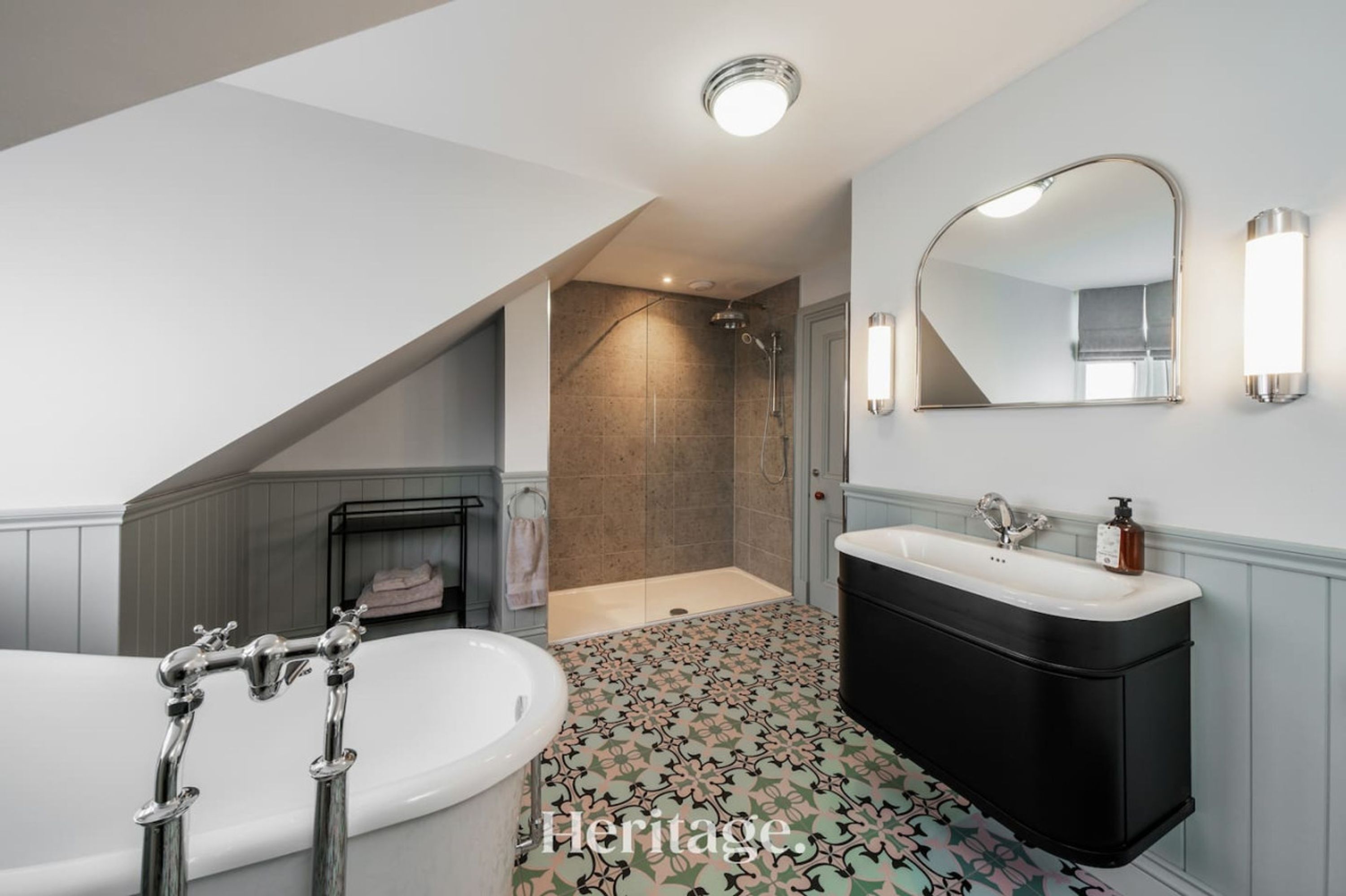 A modern bathroom with a freestanding bathtub, a black vanity, and a walk-in shower.