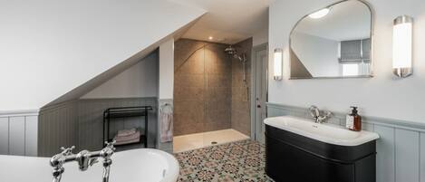 A modern bathroom with a freestanding bathtub, a black vanity, and a walk-in shower.