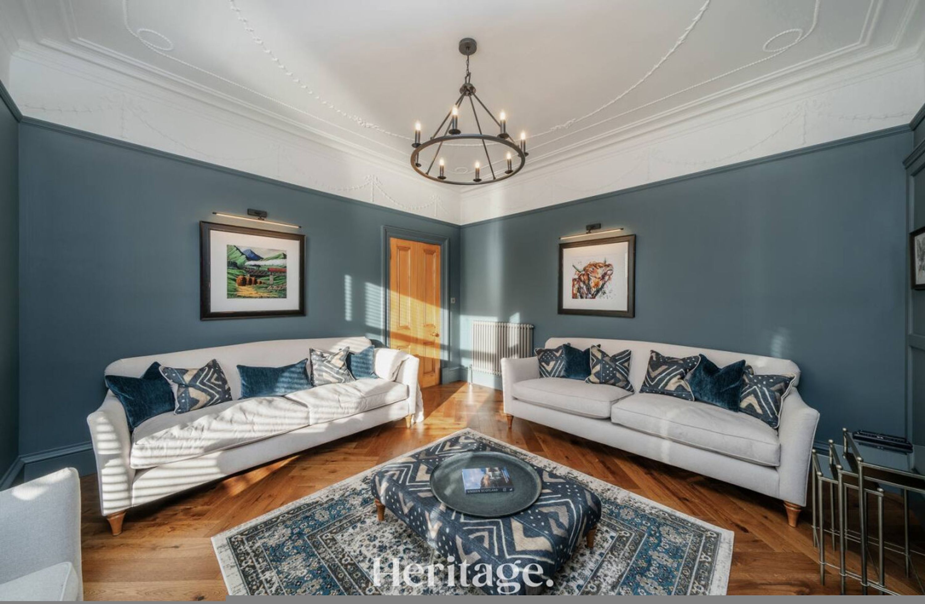 A living room with two white sofas, a patterned rug, and artwork on the walls.