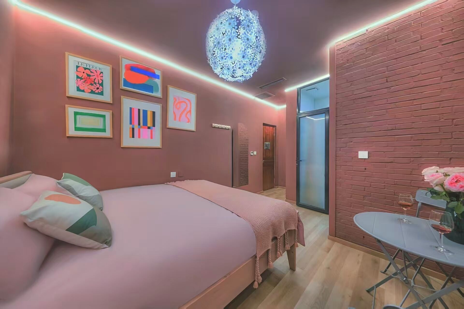 A bedroom with a bed, a small table with a glass, and a door leading to a bathroom.