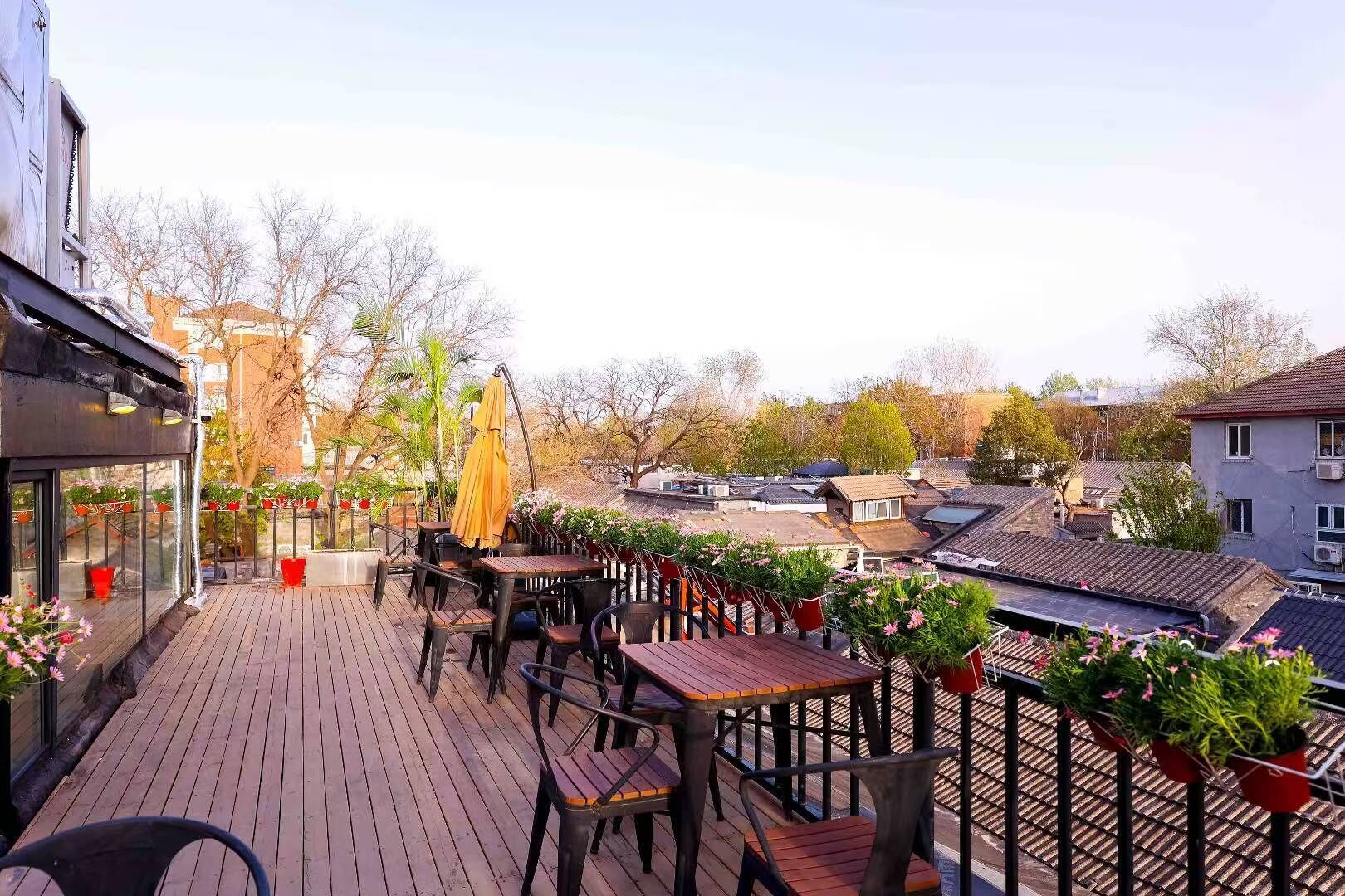 A wooden deck with outdoor seating, potted plants, and a view of residential buildings.