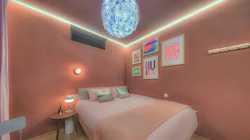A bedroom with a bed, bedside table, lamp, and wall art.