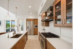A modern kitchen with stainless steel appliances, wooden cabinets, and pendant lighting.