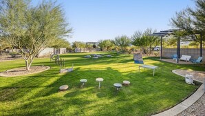 A well-maintained outdoor area with a lawn, seating arrangements, and a pergola structure.