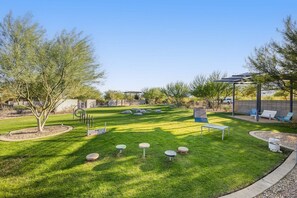 A well-maintained outdoor area with a lawn, seating arrangements, and a pergola structure. - Palladium Palace: Pool+Spa, EV Charger, Miralon! (Palm Springs)