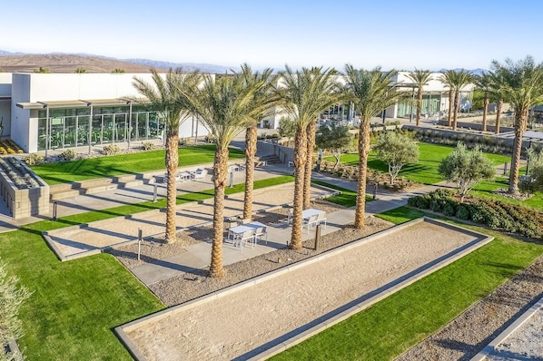 A modern building with a courtyard featuring palm trees, outdoor seating, and a well-maintained lawn.
