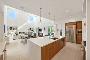 Una cocina moderna con una isla grande, electrodomésticos de acero inoxidable e iluminación colgante.