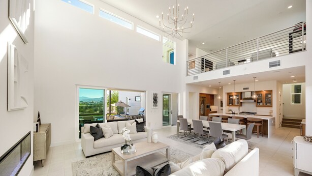 A spacious living area with a high ceiling, a dining area, and a kitchen.
