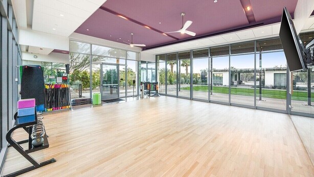 A spacious indoor area with a large window, ceiling fans, and exercise equipment.