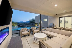 A modern outdoor living area with a pool, comfortable seating, and a view of the mountains.