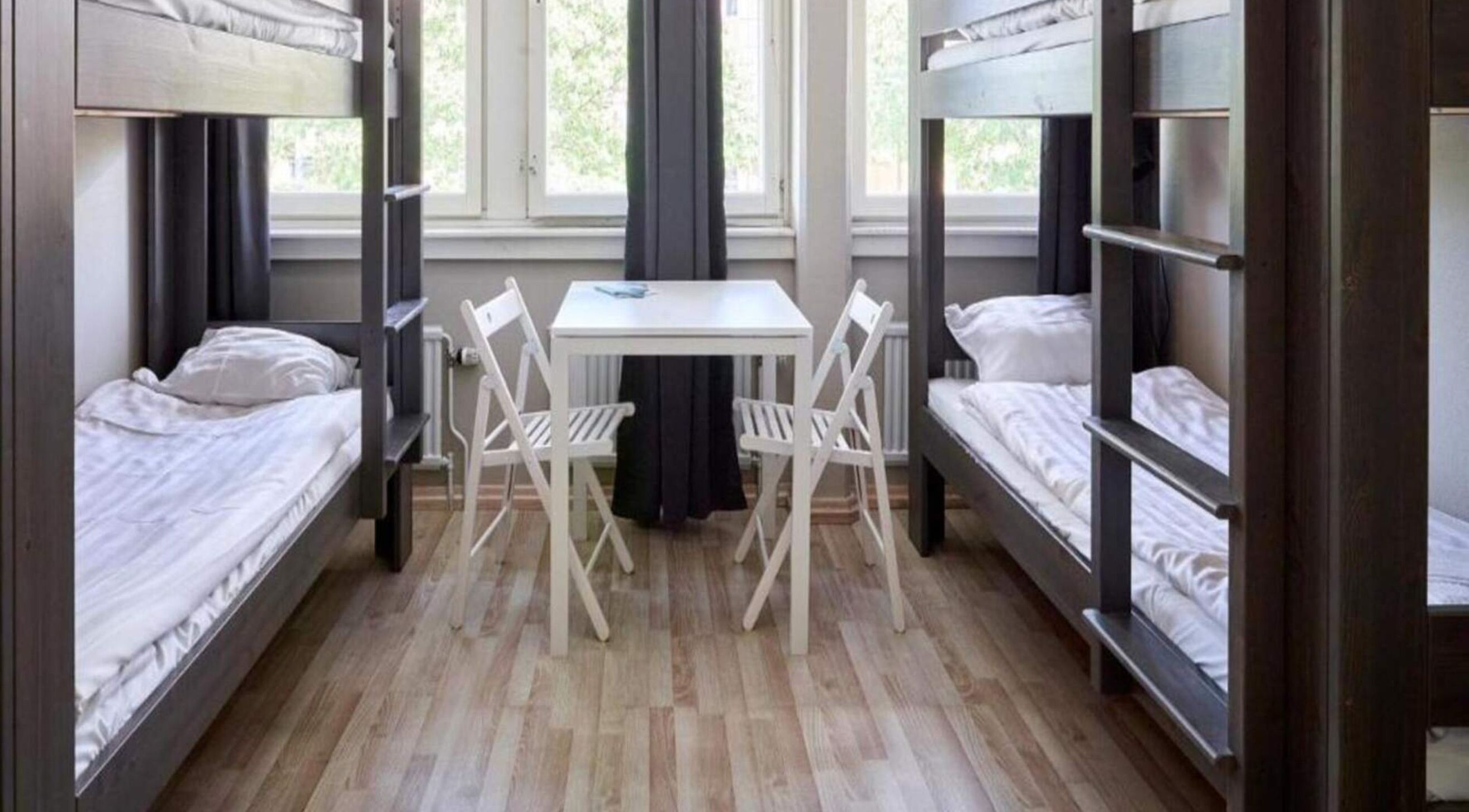 A dormitory room with bunk beds, a small table, and chairs.
