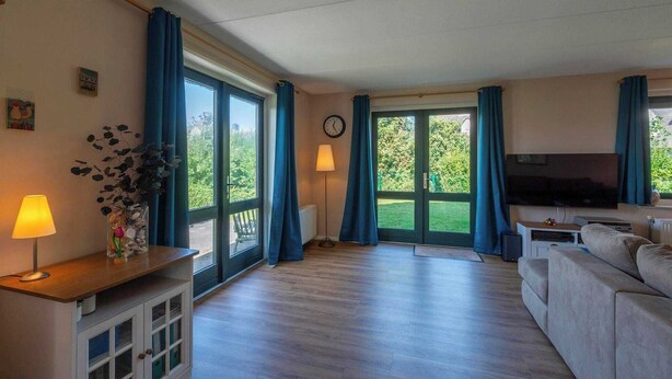 Un salón espacioso con un televisor grande, un sofá, una mesa de centro de madera y una lámpara.